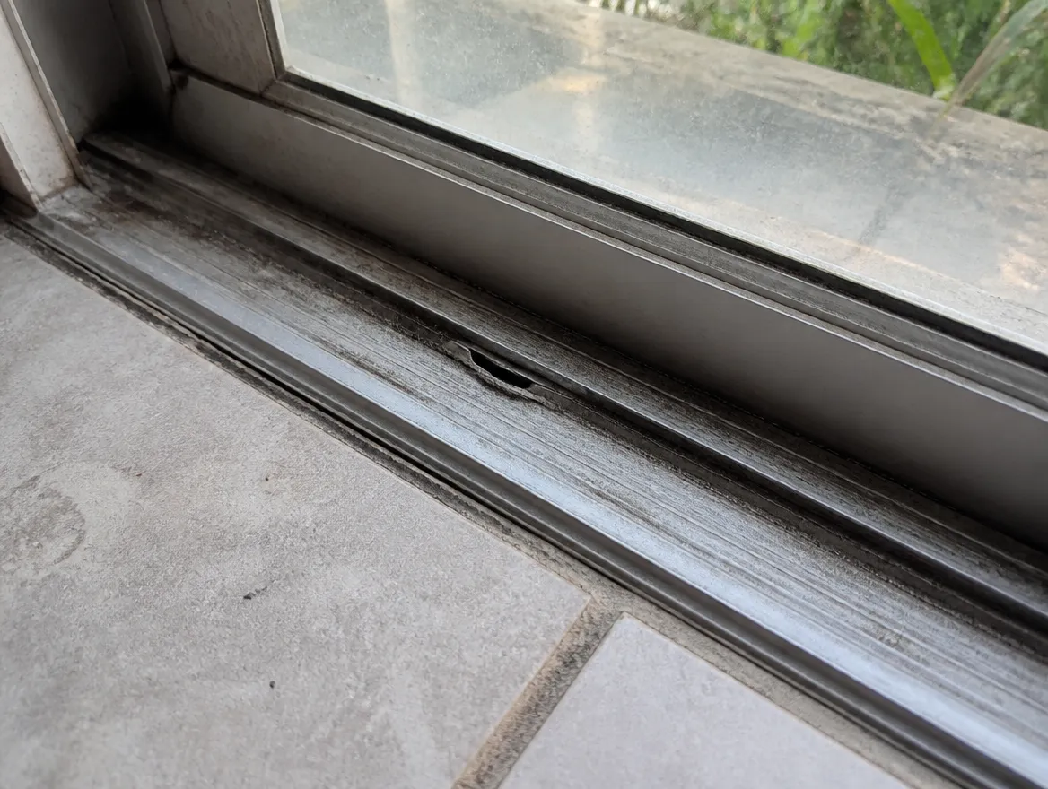 Salt-pitted aluminum sliding door track common in Palm Bay and Indian River Lagoon waterfront homes